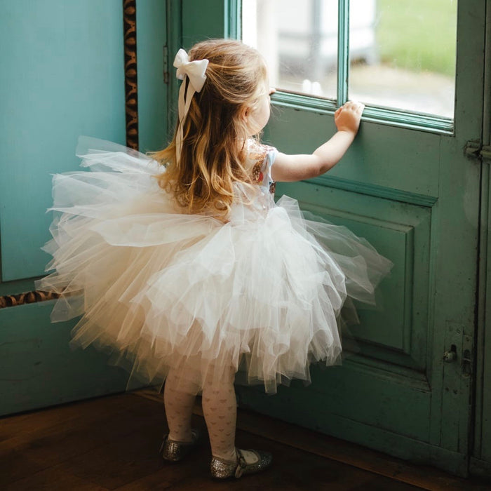 Little Love Ever After Ivory Velvet Bow Barrette worn by toddler flower girl standing at a door with ivory tutu skirt on