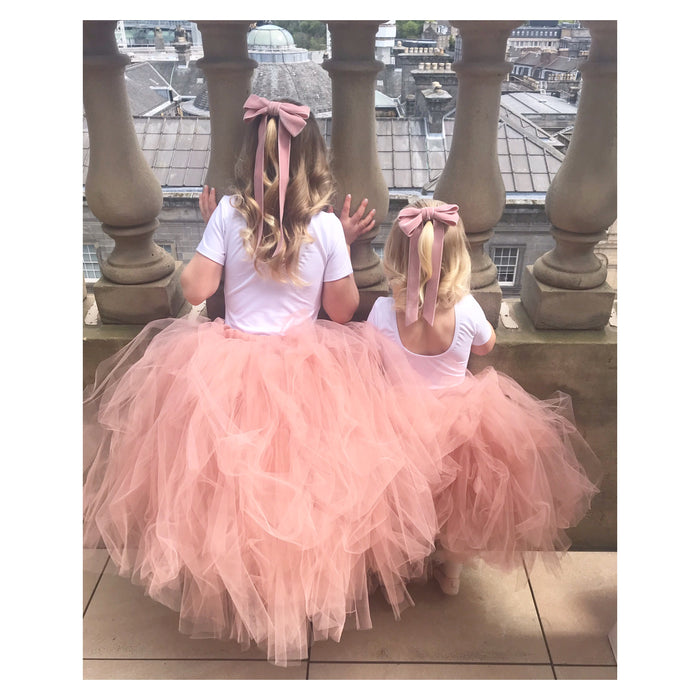 Little Love pink velvet bow hair bow barrettes worn by blonde sisters looking over balcony at wedding wearing pink tutu skirts and Ever After Velvet  hair bows in gently curled wedding hair, flower girls bow in blush pink 