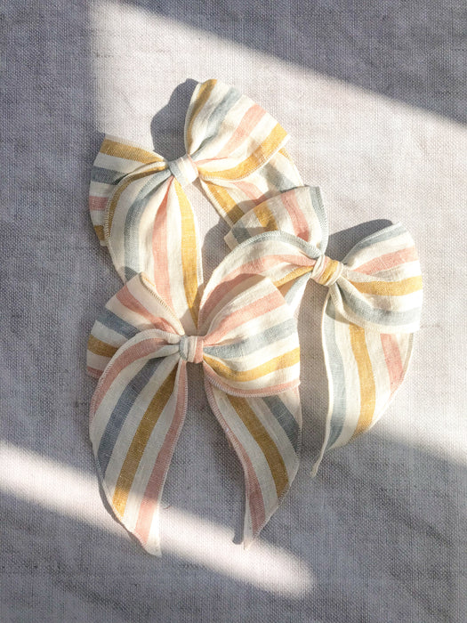  rainbow stripe linen bow hair clip for girls, rainbow cotton bow hair clips, muted rainbow hair bow, neutral rainbow bow hair clips, little love handmade hair bows, childrens hair accessorries uk, luxury kidswear uk, girls hair bows, mustard rainbow hair bow, linen hair bow, hair bows uk, stripe linen bow 