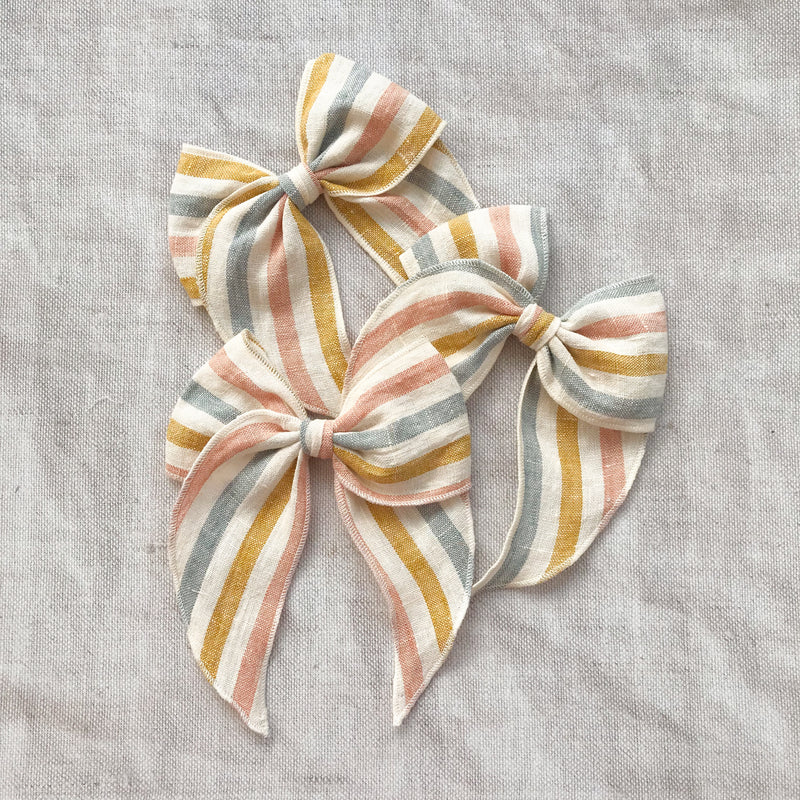  rainbow stripe linen bow hair clip for girls, rainbow cotton bow hair clips, muted rainbow hair bow, neutral rainbow bow hair clips, little love handmade hair bows, childrens hair accessorries uk, luxury kidswear uk, girls hair bows, mustard rainbow hair bow, linen hair bow, hair bows uk, stripe linen bow 